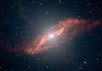 Изображение массивной галактики и ее пылевой структуры, причудливо искривленной в виде параллелограмма, полученное "Спитцером".