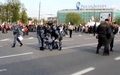 Артем Савелов. Омоновец роняет рацию. Рядом задерживают человека полицейские в серой форме. Кадр видео