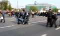 Артем Савелов. Омоновец поднимает рацию. Рядом проводят задержание полицейские в серой форме. Кадр видео